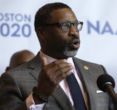 A man in a suit at a microphone.
