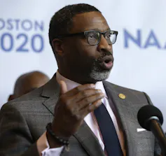 A man in a suit at a microphone.