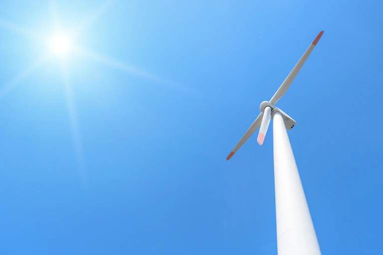 wind turbine against blue sky and sun