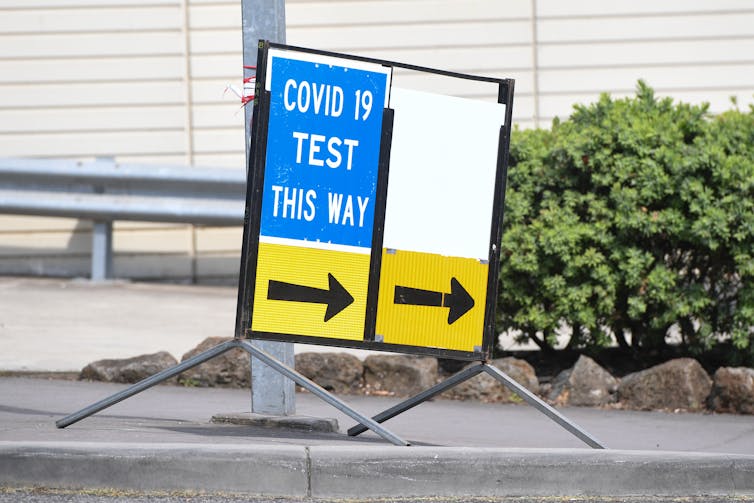 A sign saying 'COVID-19 test this way'.