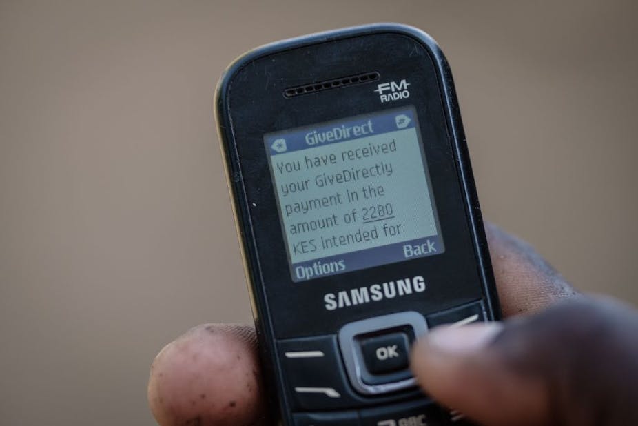 Hand holding cellphone with a message on the screen confirming a universal basic income transaction