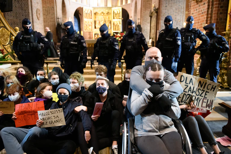 Protestors wearing masks sit in front of advancing police.