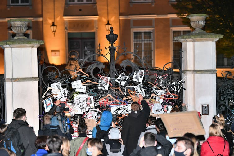 A group of people attach hangers to a gate.