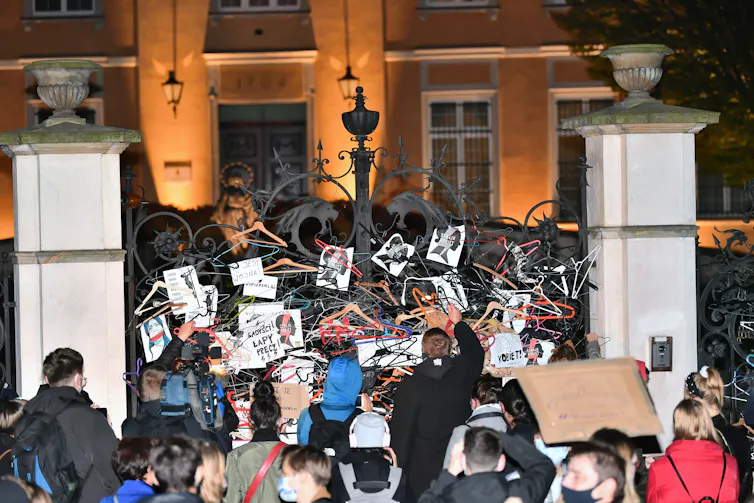 A group of people attach hangers to a gate.
