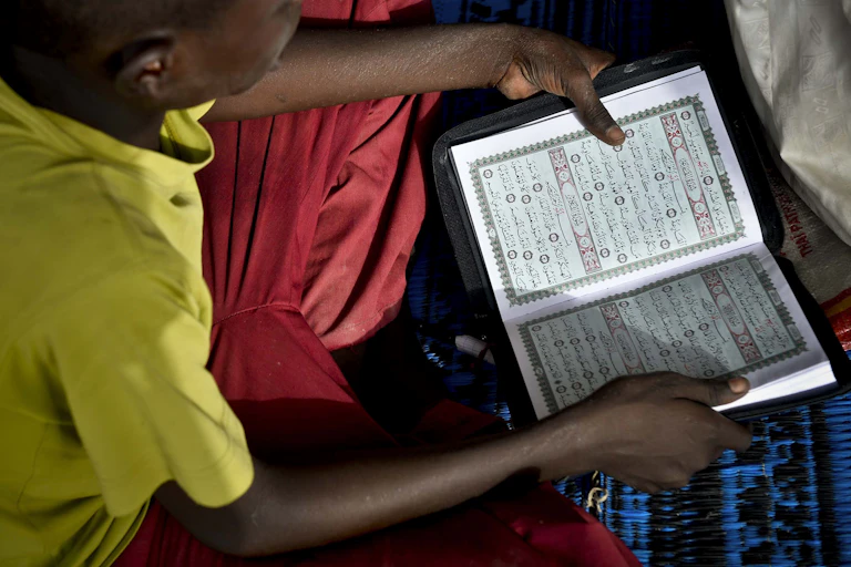 A young boy reading, seen from above and dressed in bright colours..