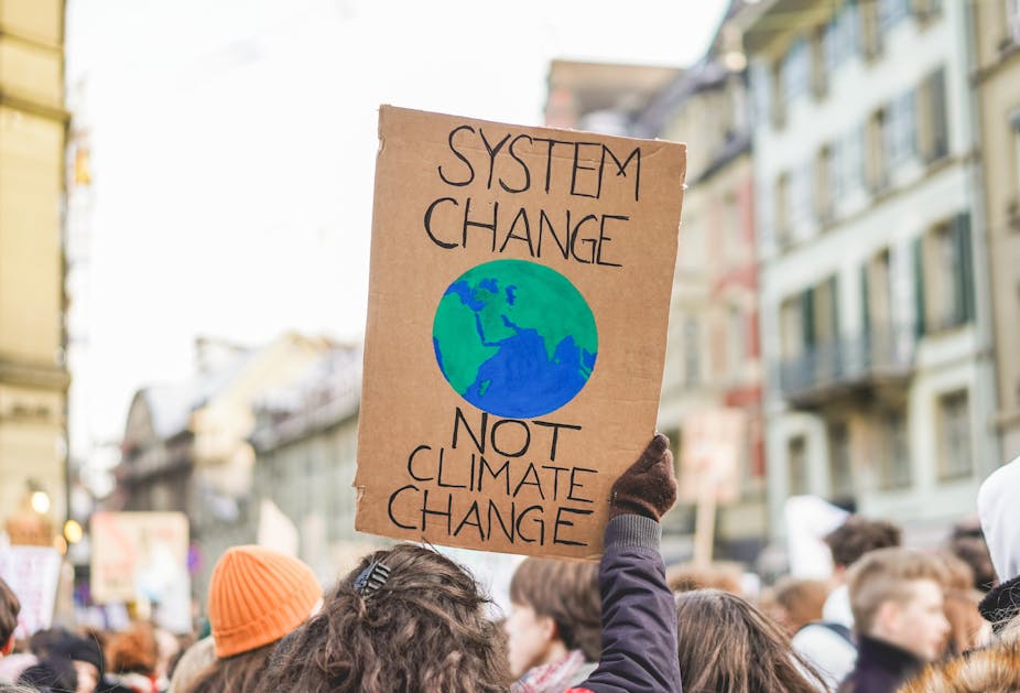 A protester holding a placard that says "System change not climate change"
