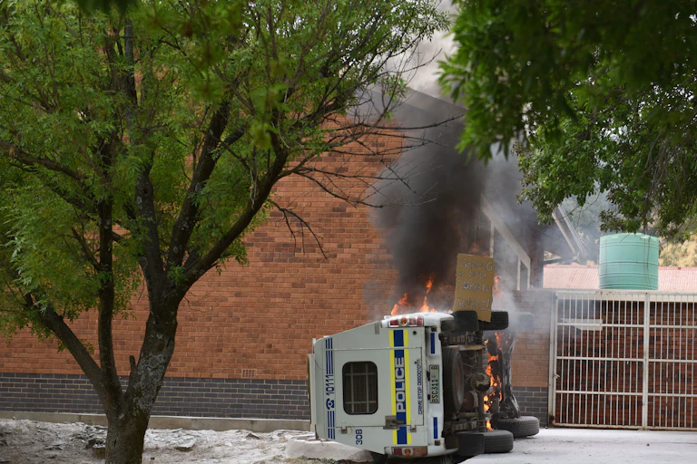 A while police van lies on its side and in flames after protesting farmers set it alight