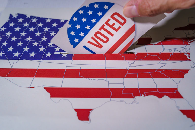 Hand posting 'I voted' sticker through image of US with flag on it.
