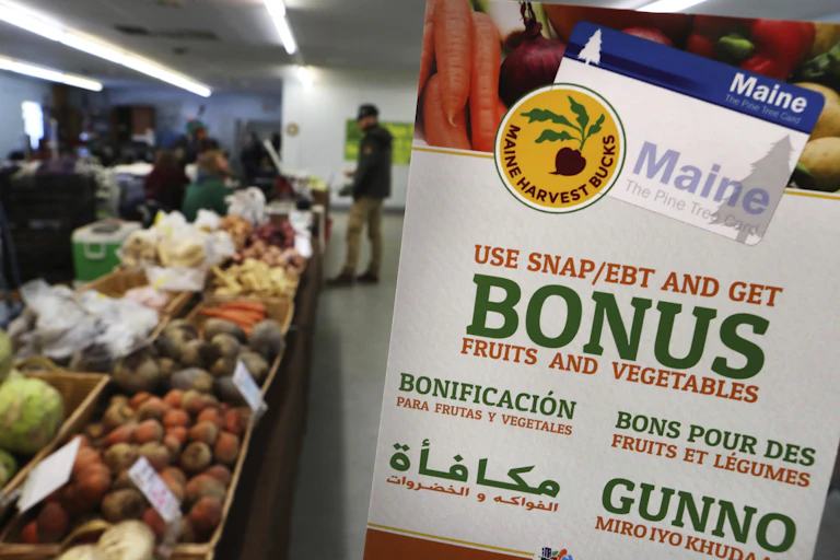 Fruits and vegetables in boxes next to a sign in multiple languages.