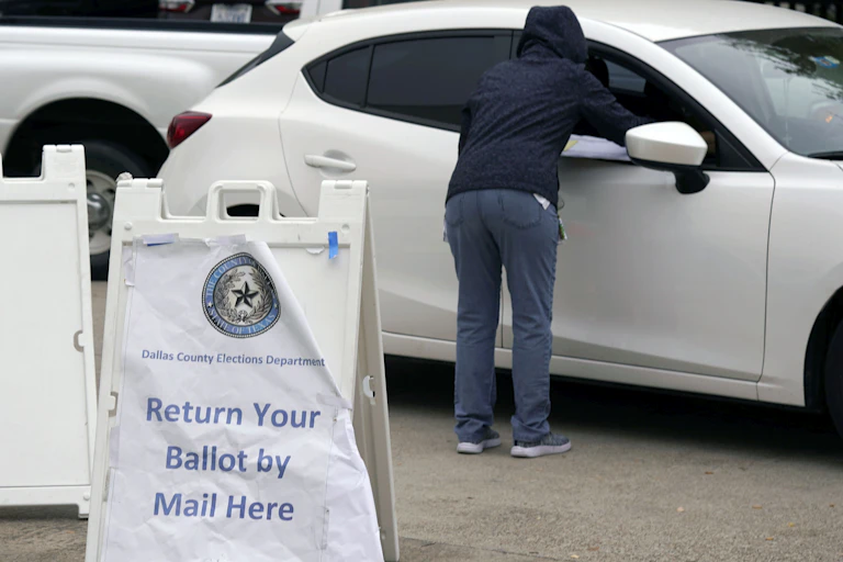 An election worker accepts a ballot from a voter