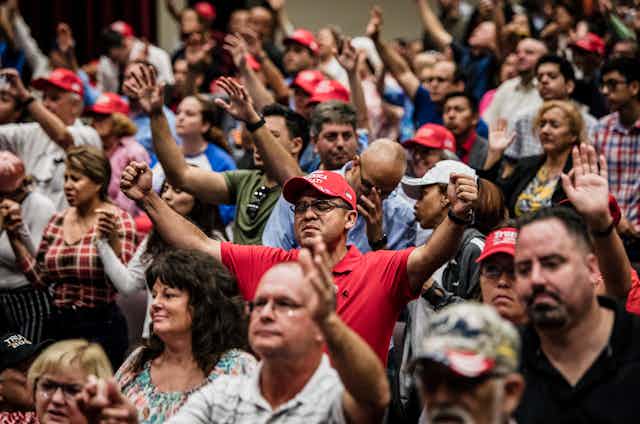 Attendees pray together before President Donald Trump addresses the crowd at the King Jesus International Ministry during a "Evangelicals for Trump" rally in Miami.