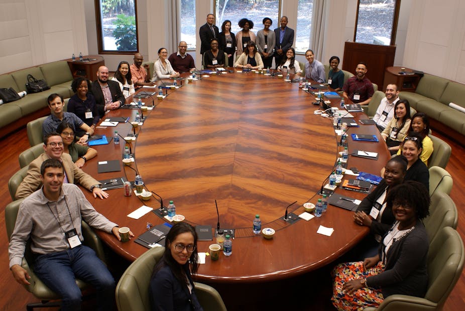 Minority and underrepresented scholars seated and standing around a board room table