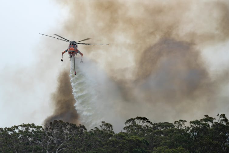 Helicopter dumping water over bushfires