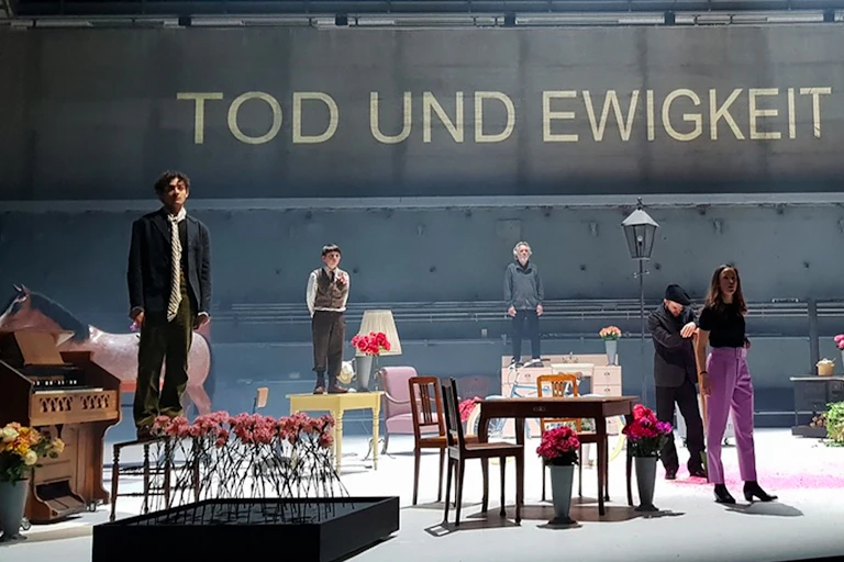 Production image, cast on stage looks to audience