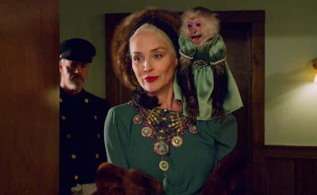 Expensively dressed woman with monkey on her shoulder.