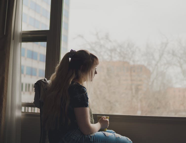 Woman sitting by window with cup of tea