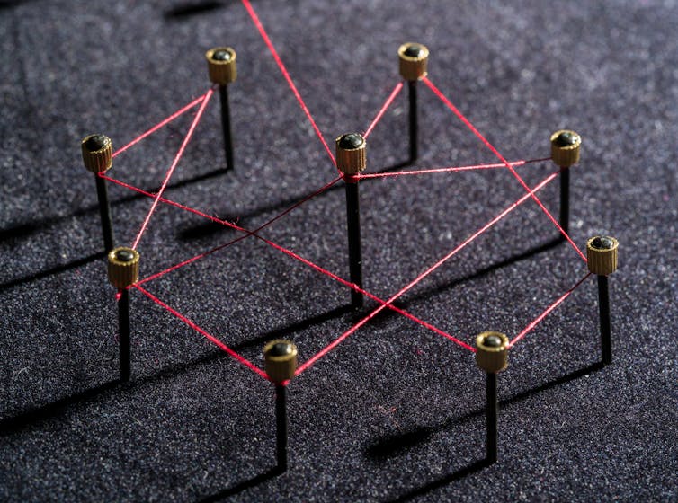 Nine pins connected be red string.