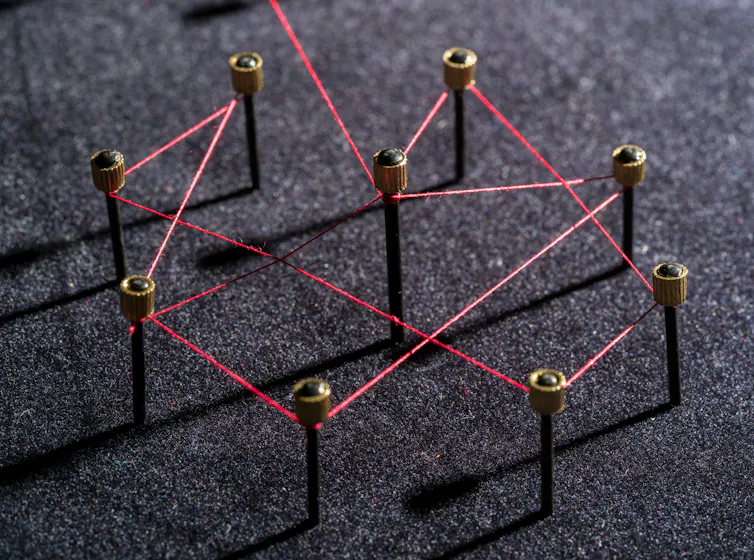 Nine pins connected be red string.