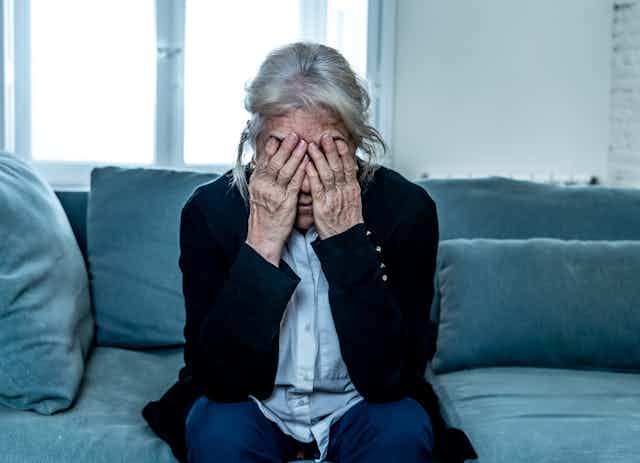 Lonely depressed senior old widow woman crying on couch in isolation at home