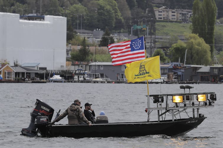 A boat flies the Gadsden ‘Don't tread on me’ flag and a Three Percenters flag.