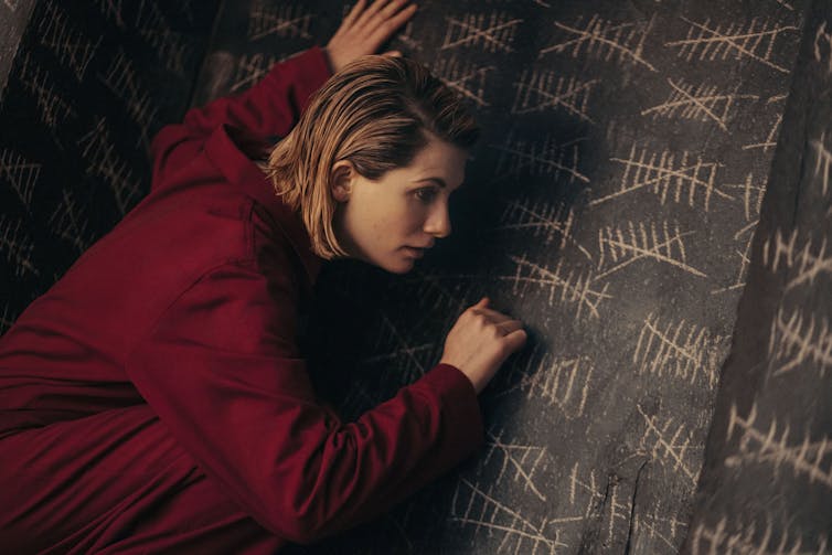 Actress Jodie Whittaker writing on a blackboard.