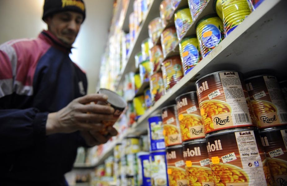 Un commerçant range une boite de conserve de nourriture halal dans un rayon
