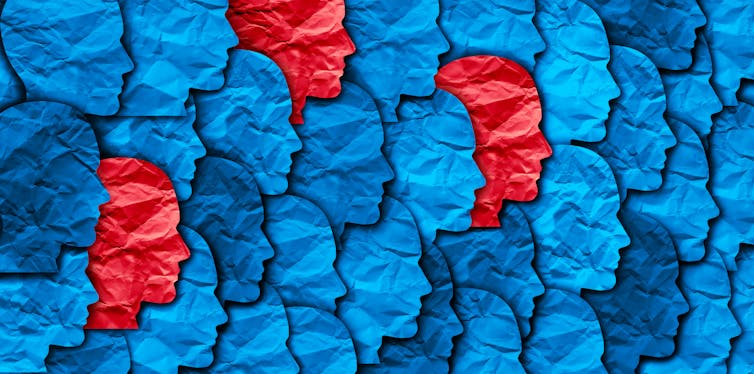 A graphic showing a collage of blue paper faces with a few isolated red faces