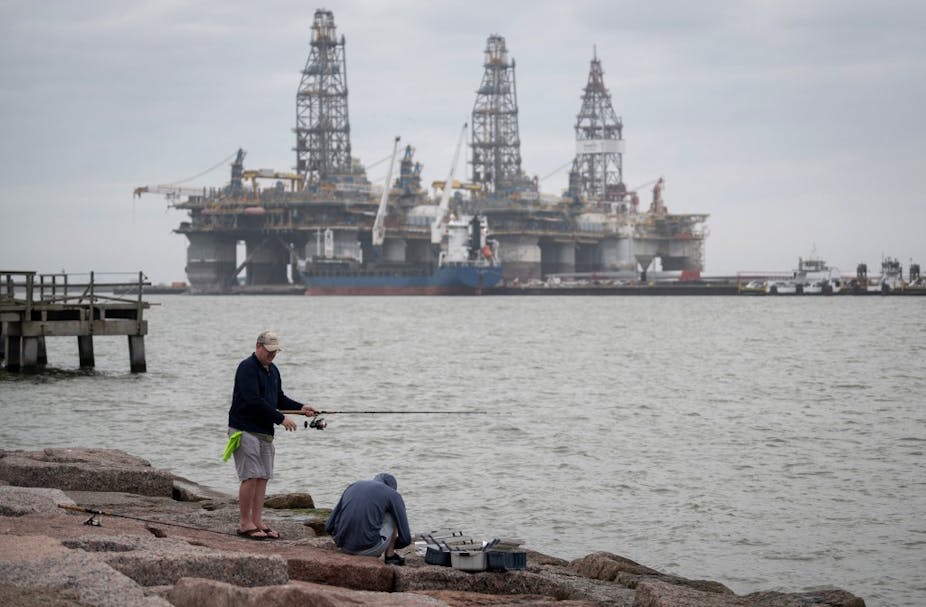 Fishermen on the shore by decommissioned oil rigs in Port Aransas, Texas