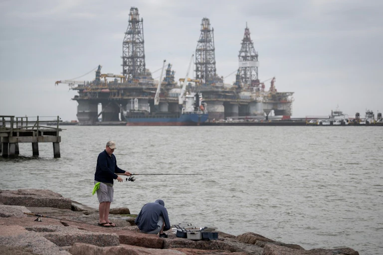 Fishermen on the shore by decommissioned oil rigs in Port Aransas, Texas