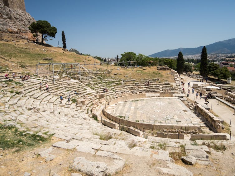 A photos of the ruins of the Theater of Dionysus showing rows upon rows of seats made of marble.