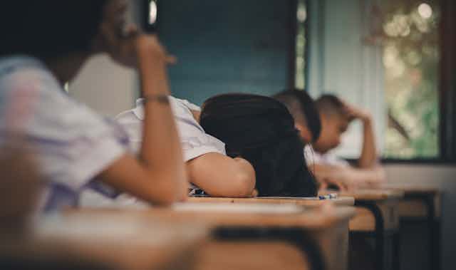 Students with her head down on a desk.