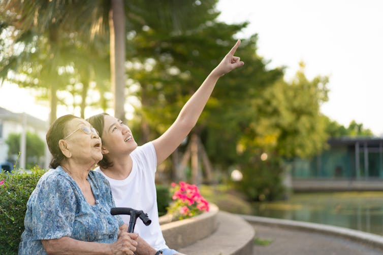 Old and young women sit together in a garden