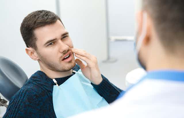 Young man sitting in dentist chair with toothache