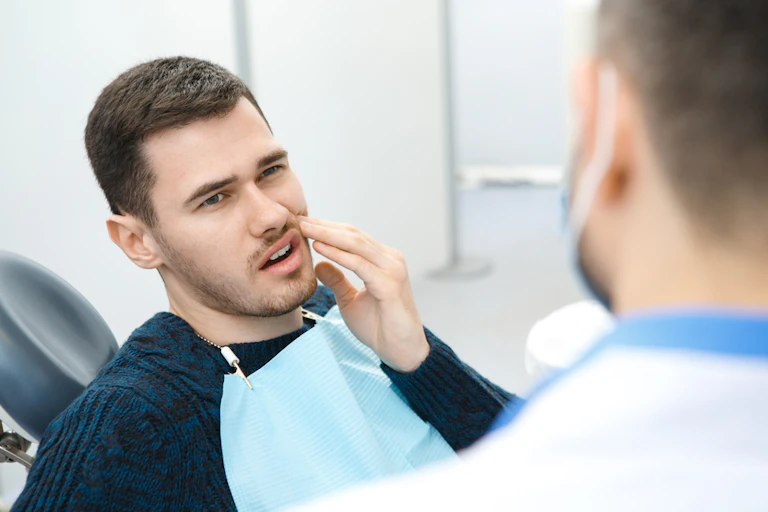 Young man sitting in dentist chair with toothache