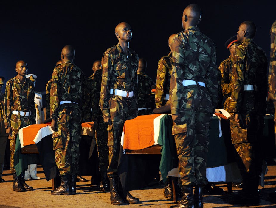 Soldiers stand guard over flag-draped coffins