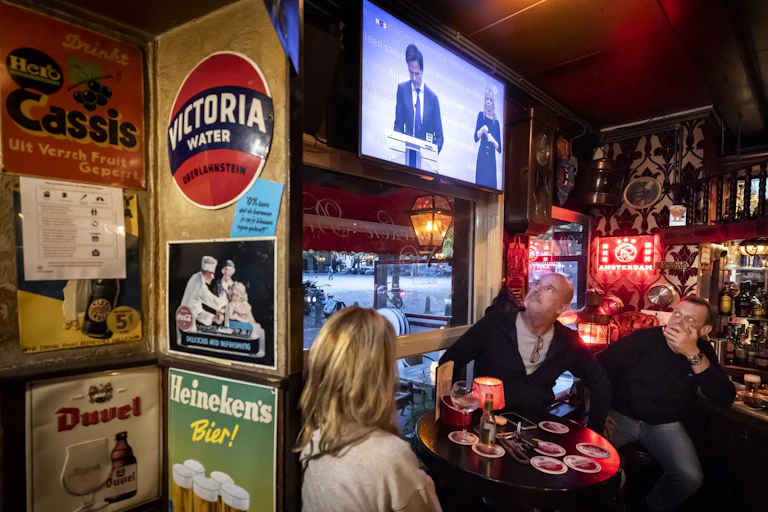 A group watches on a TV screen as the Dutch government gives an update about the coronavirus.