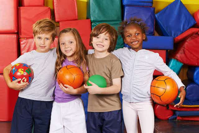 Children together in sports hall with balls