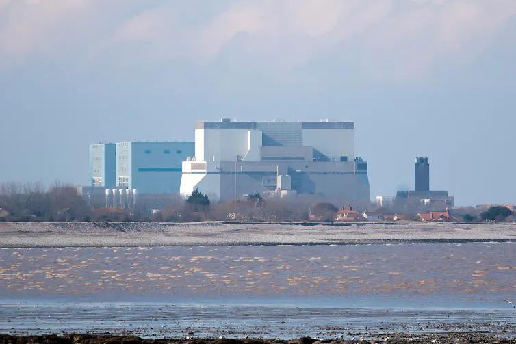 Hinkley Point C power station (a squat building) overlooks a mudflat.