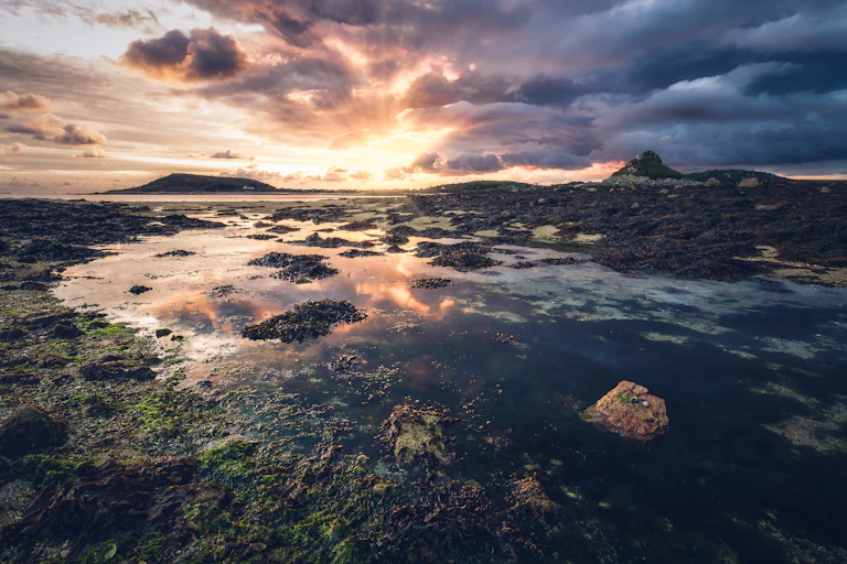 View of sunset over tidal beach.
