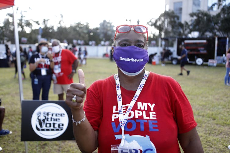 A woman wears a mask and a Let My People Vote T-shirt.