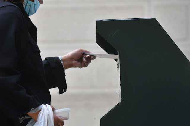 A woman puts a ballot in a box