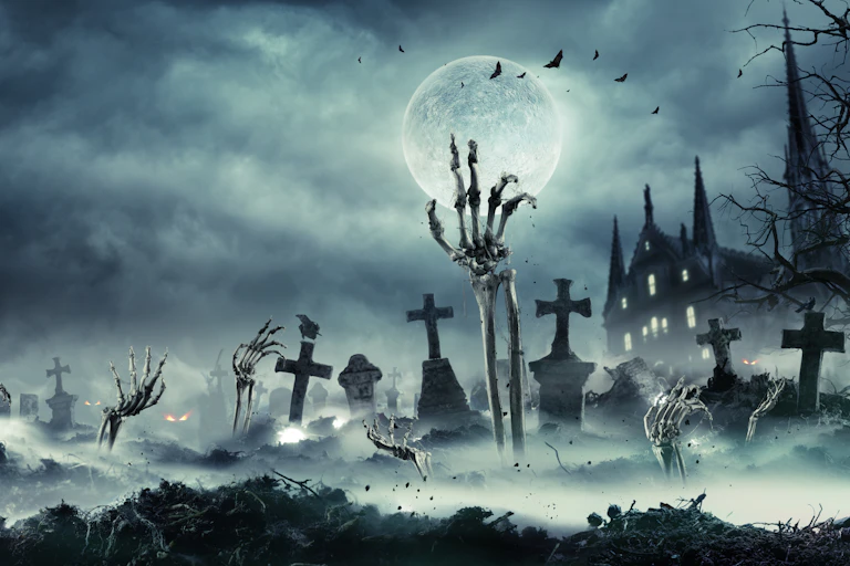 A skeletal hand reaching out of the ground in a spooky graveyard.