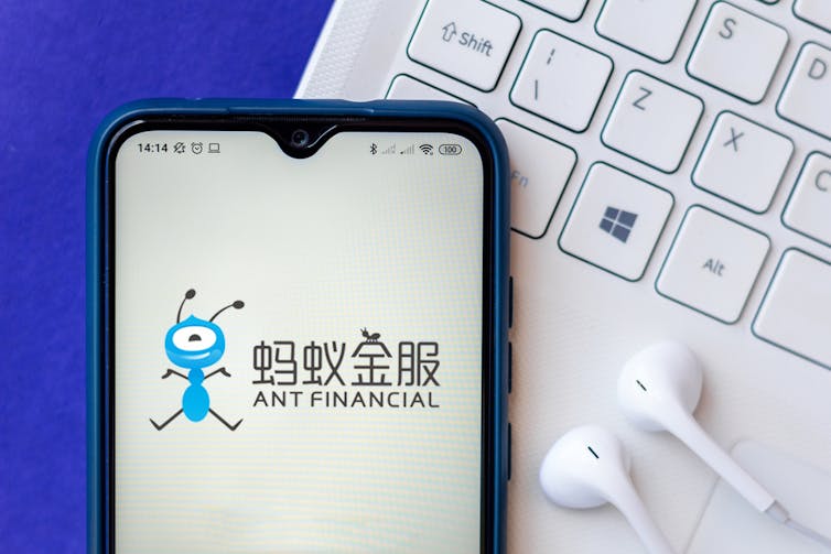 Mobile phone with Ant Financial app in front of keyboard and headphones