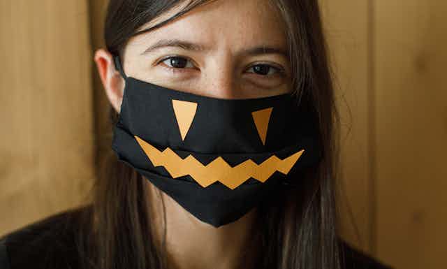 Woman wearing a mask decorated with a pumpkin face