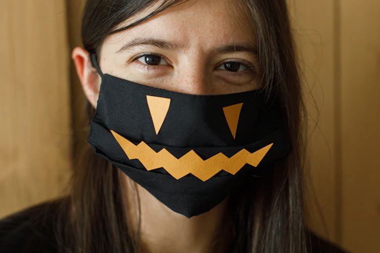 Woman wearing a mask decorated with a pumpkin face