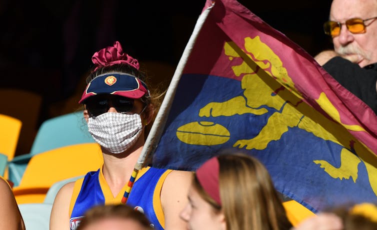 Woman wears a mask during a Lions AFL game at the Gabba in Brisbane.