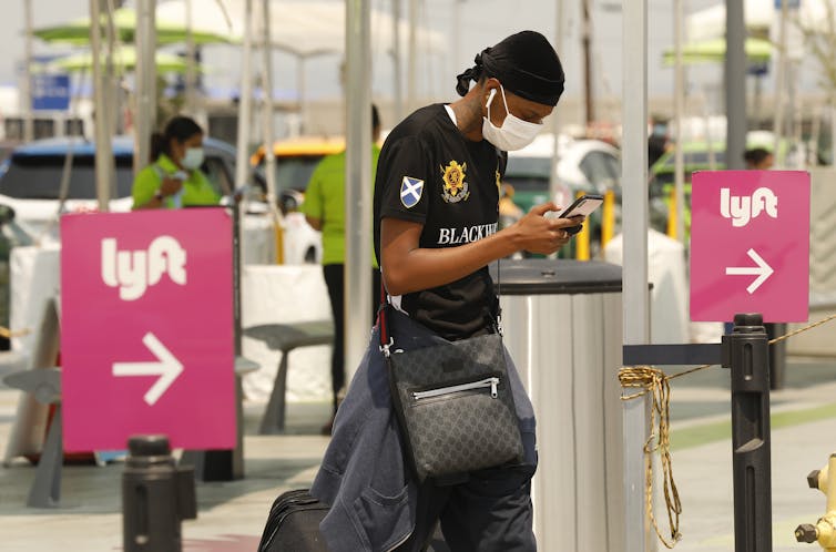 A man checks his phone to locate his Lyft driver at Los Angeles International Airport