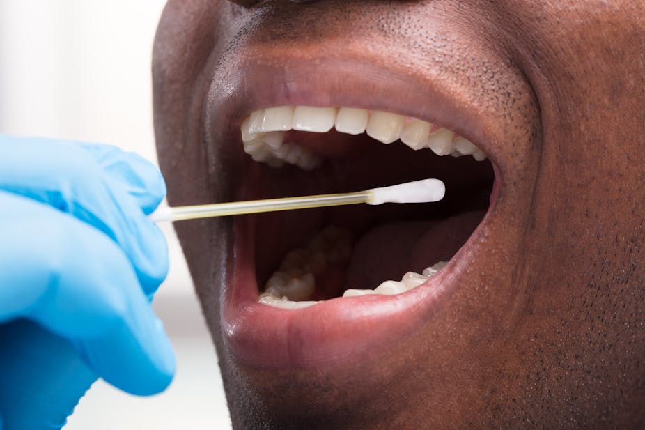 A gloved hand inserts a swab into a person's open mouth