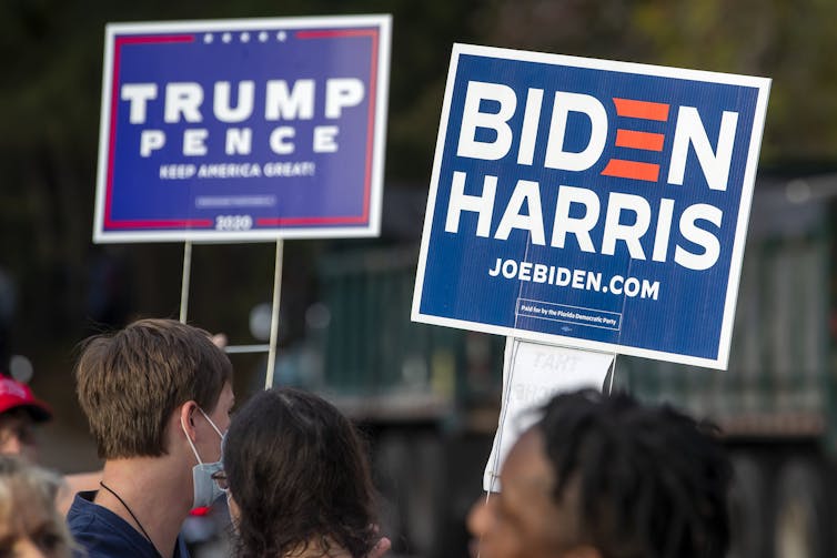 People holding Trump/Pence and Biden/Harris signs.