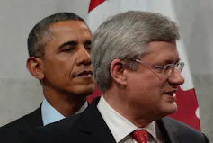 Barack Obama stands behind Stephen Harper.